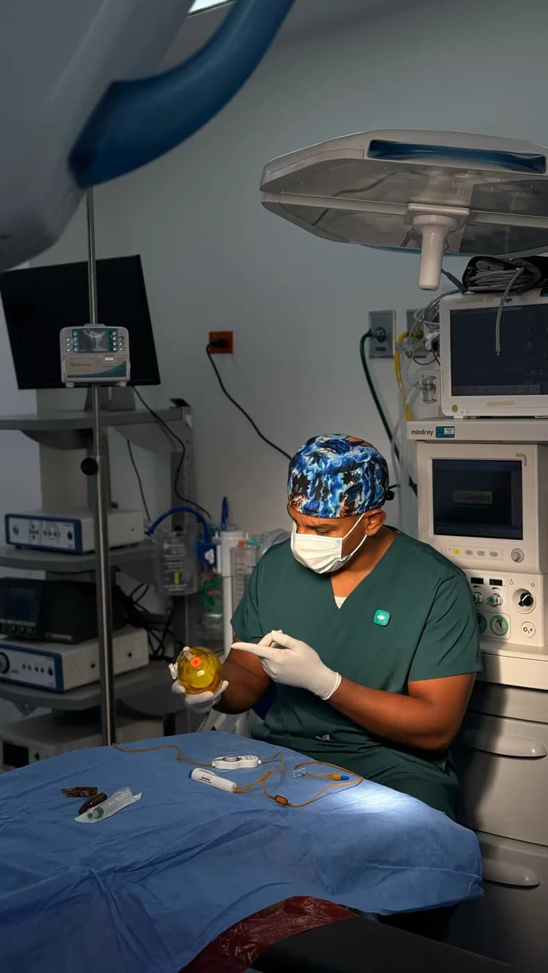El Dr. Camelo revisa el circuito y la mascarilla con el monitor de constantes al fondo.