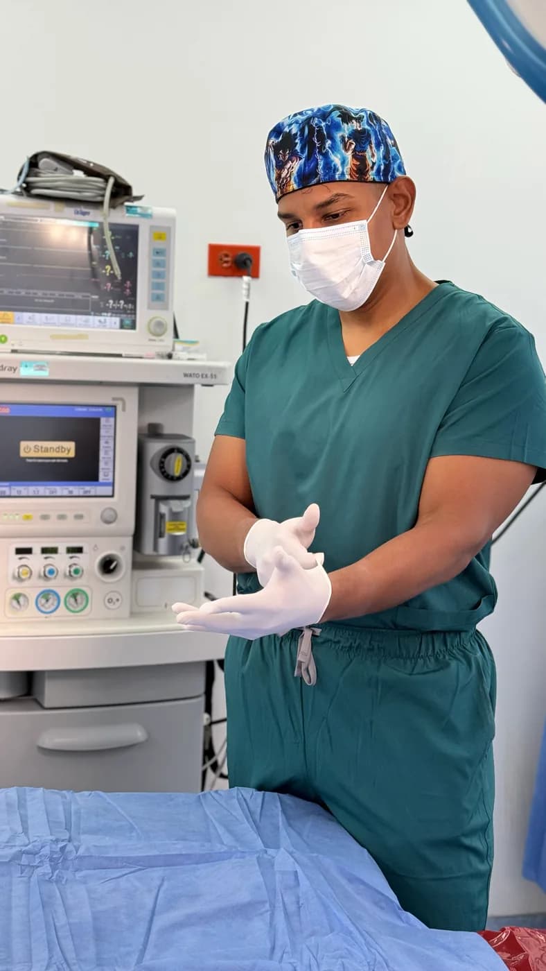 El Dr. Camelo se enguanta junto a la máquina de anestesia antes de un procedimiento.
