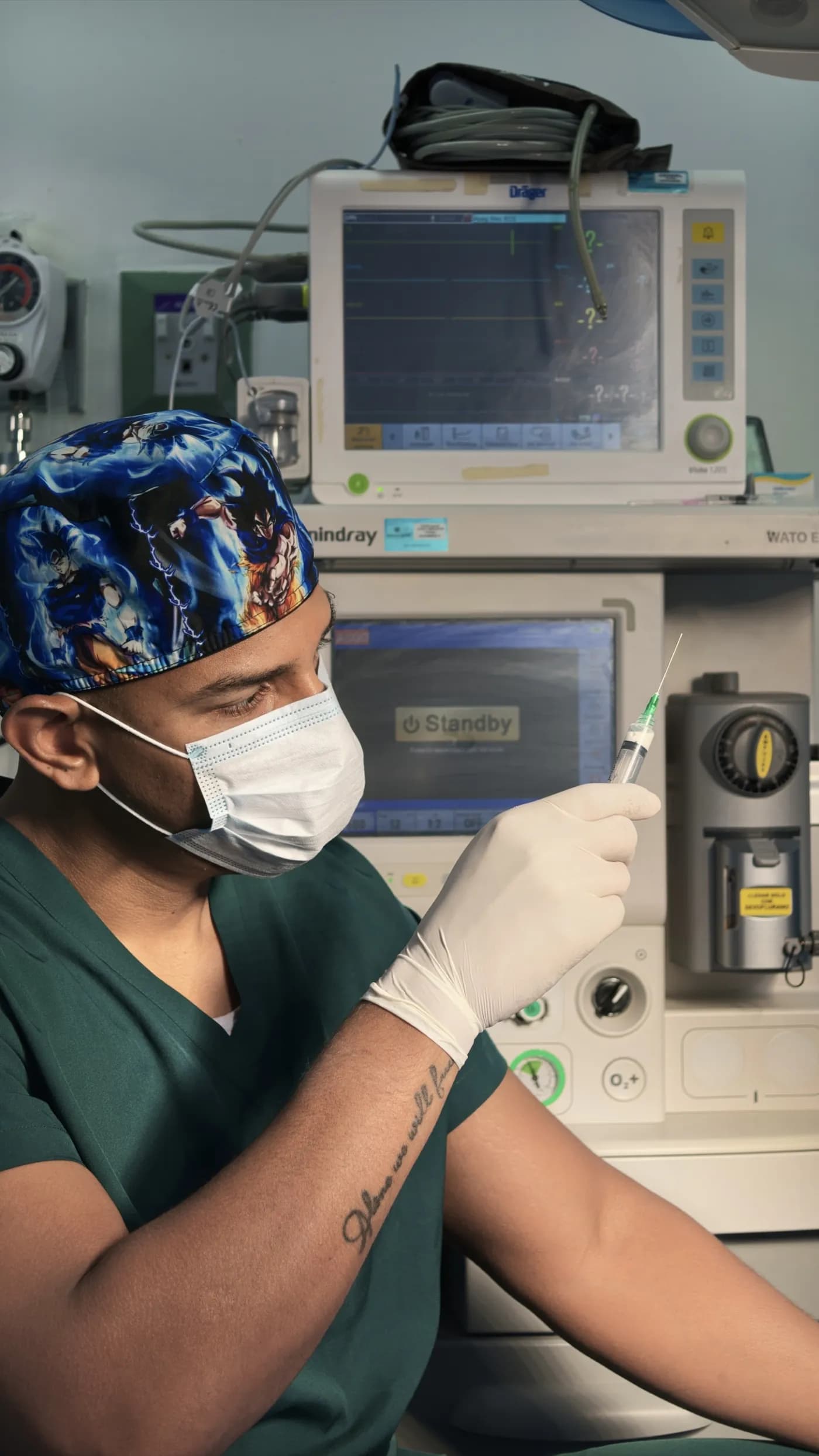 El Dr. Camelo prepara una jeringa frente a la máquina de anestesia y el monitor de constantes.